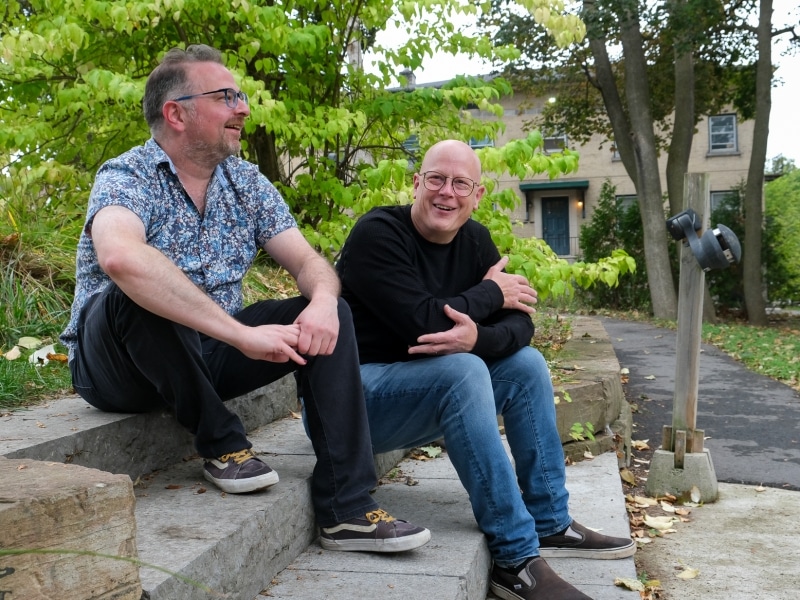 Gabe Pollock and David Tough are sen sitting on a set of outdoor steps.
