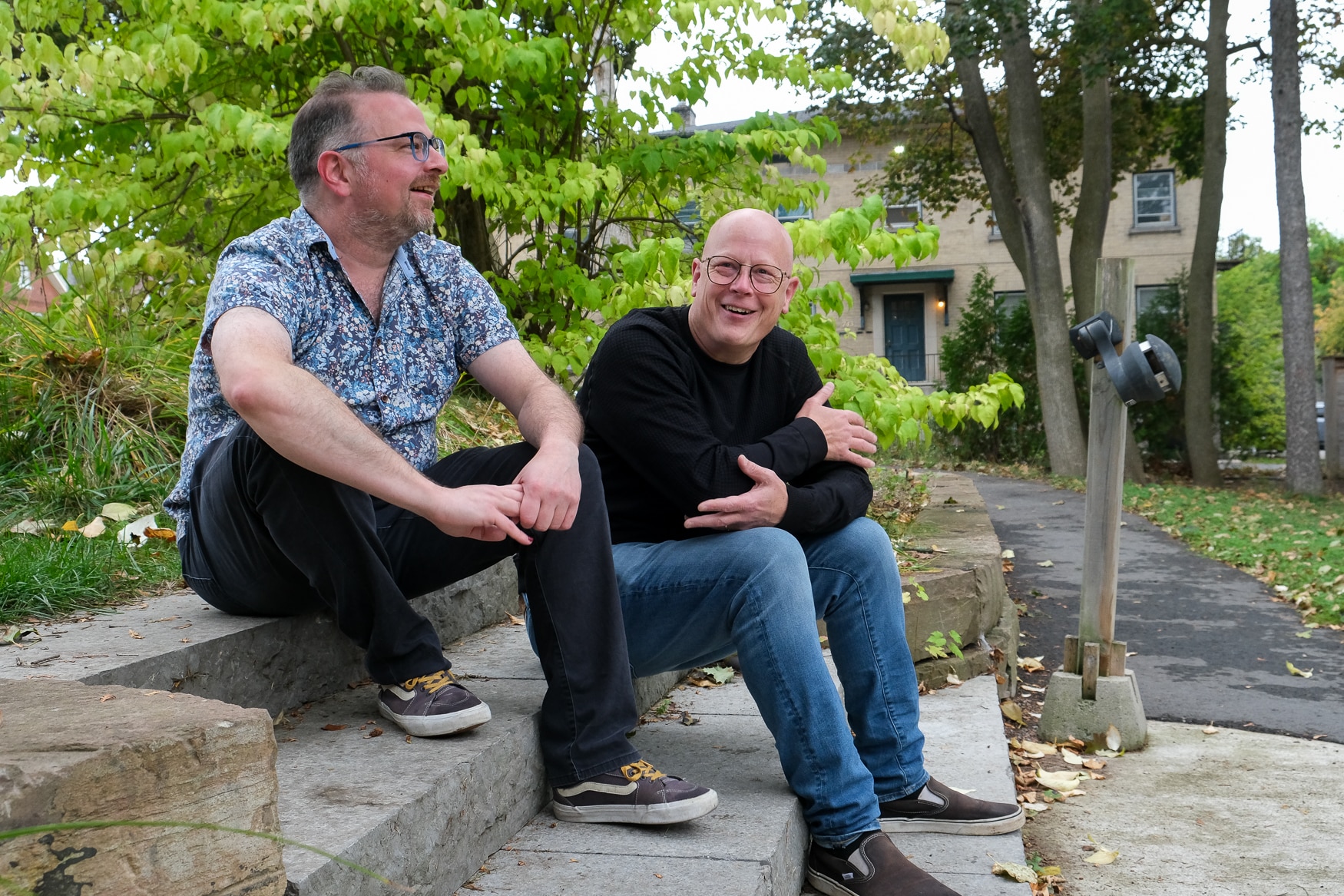 Gabe Pollock and David Tough are sen sitting on a set of outdoor steps.